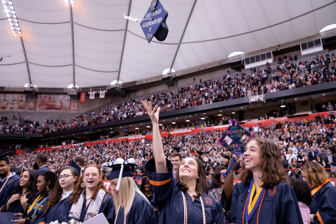 Student throwing cap in the air, 2019 Syracuse University
